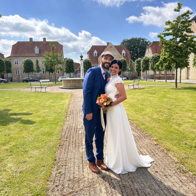 Frisch verheiratetes Paar steht im Freien vor einem Gebäude.