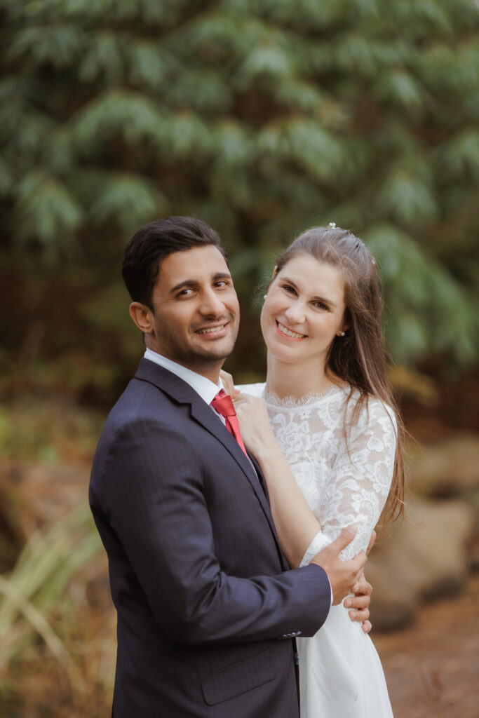 Heiraten in Dänemark: Ein glückliches Brautpaar lächelt verliebt nach der Hochzeit im Grünen.