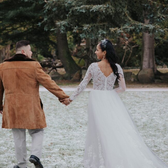 Heiraten in Dänemark: Ein Brautpaar spaziert durch eine verschneite Landschaft, Hand in Hand nach der Hochzeit.