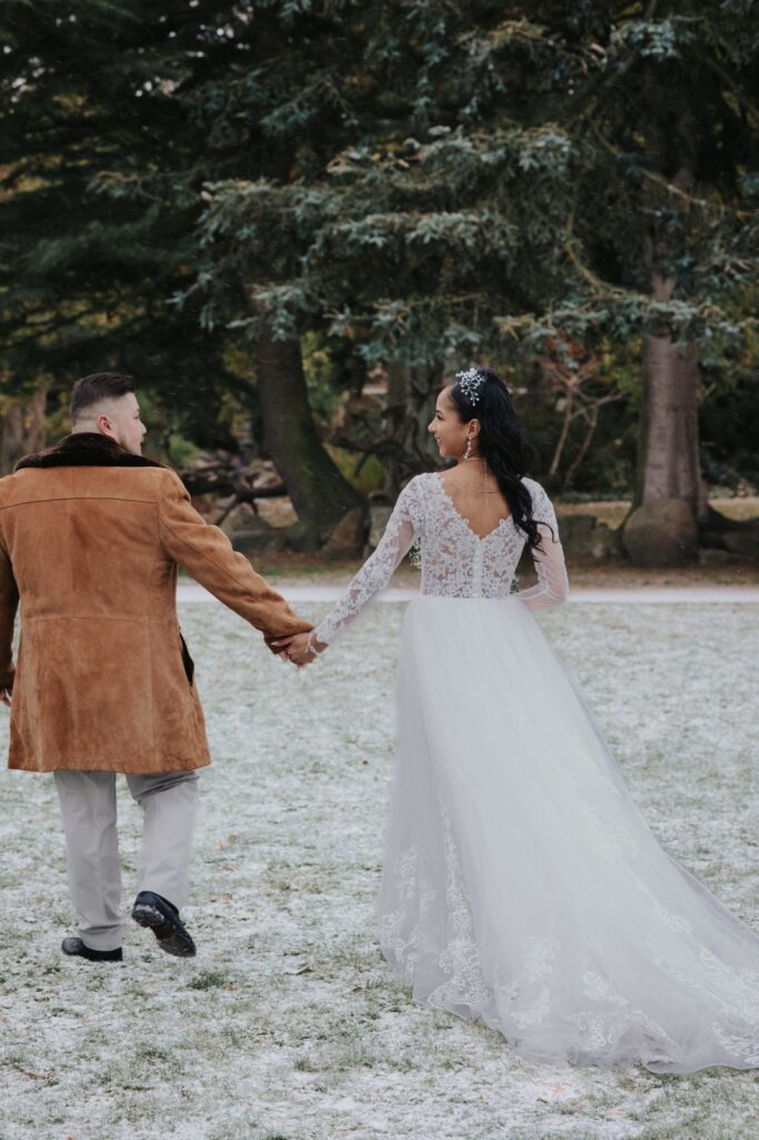 Heiraten in Dänemark: Ein Brautpaar spaziert durch eine verschneite Landschaft, Hand in Hand nach der Hochzeit.